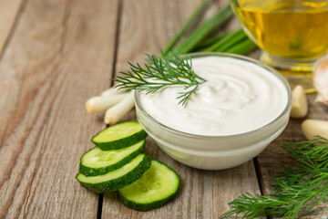 Cucumber sour cream tzatziki sauce on a wooden table.Tartar sauce. Traditional delicious appetizer. yogurt sauce. Tzatziki with ingredients cucumber, garlic,dill,lemon,mint. salad dressing.Copy space