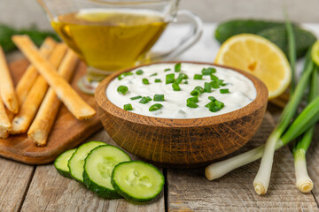 Cucumber sour cream tzatziki sauce on a wooden table.Tartar sauce. Traditional delicious appetizer....