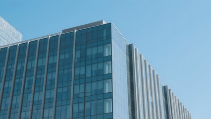 Obraz premium Modern multi-story building with reflective glass windows under a clear blue sky