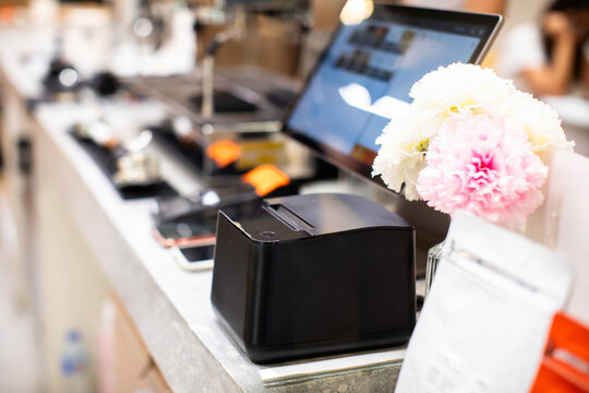 Selective focus to printer of POS set with blurry computer. Point of sale system for retail stores or restaurants. Receipt printer to shopping invoice and touch screen display.