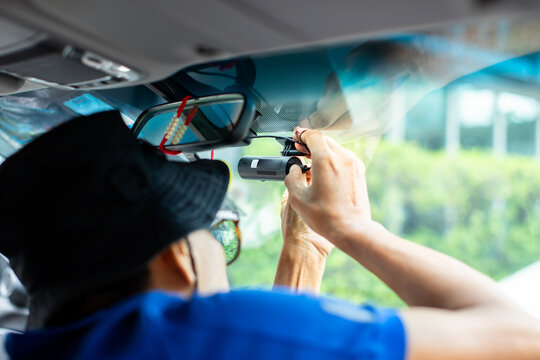 selective focus to Car CCTV camera video recorder. The technician is installing front camera car, Car camera for safety on the road.  Dashcam in front of car to record evidence in emergency.