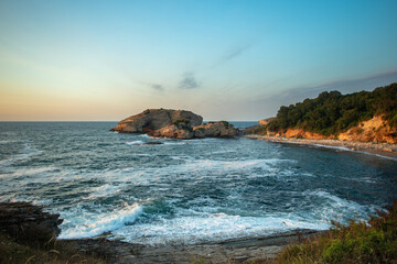 Scenic rocky coastline with calm sea and forest background at Sardala Bay Kocaeli - peaceful beach landscape on sunny day with dramatic rock formations