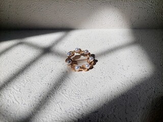 Pearl and Gold Brooch: Elegant Jewelry on Textured Surface