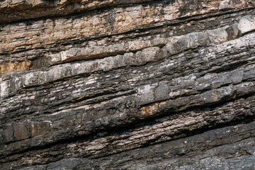Layered volcanic rock formations with sedimentary strata patterns on coastal cliffs at Sardala Bay, Kocaeli, Turkey - natural geological texture background