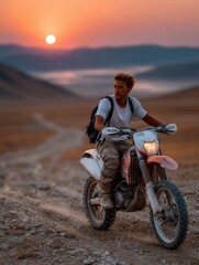 Young man riding motorcycle on rough dirt trail during sunset in open landscape