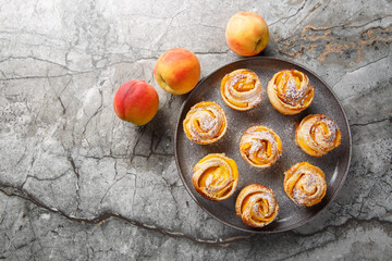 Peach roses mini tarts muffins made of puff pastry with powdered sugar close-up on a plate on the table. horizontal top view from above