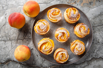 Fresh puff pastry peach mini tarts muffins close-up on plate on table. horizontal top view from...