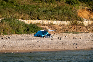 Blue camping tent setup on sandy beach with folding chairs at secluded waterfront campsite in Sardala Bay, Kocaeli, Turkey - peaceful outdoor adventure scene