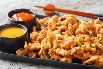Little Crispy Pork or xiao su rou is a Sichuan dish of small strips of battered and fried pork closeup on the plate on the table. Horizontal