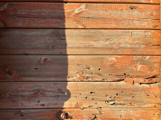 A close-up of weathered wooden planks with peeling orange paint and visible grain, offering a rich...