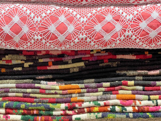 A meticulously stacked display of traditional Moldovan embroidered pillows in red and white atop...