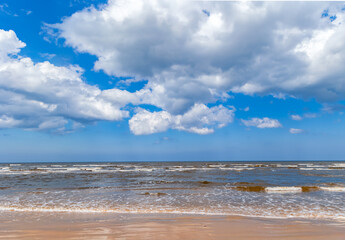Panorama of a deserted beach on the Baltic Sea with fluffy clouds in the sky in Jurmala, Latvia