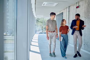 Group of multi-ethnic businesspeople discussing during a coffee break in the hallway of a modern...
