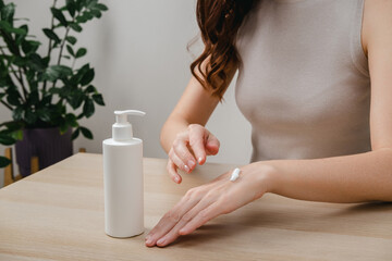 Female hands applying moisturizer cream or lotion. Hand skin care, treatment skin care body concept. Routine in the morning