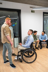 Young man in wheelchair discussing with colleagues in a modern coworking office, showcasing...