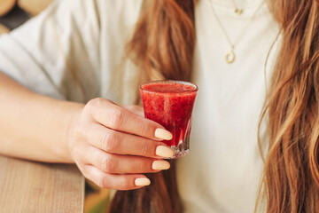Woman holding fruit vodka shot. Frozen blended berries with alcohol. Summer party drink idea....