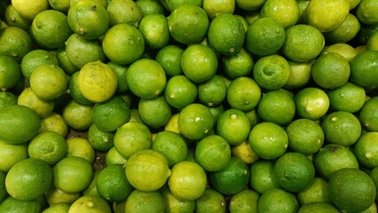 Fresh limes stacked in abundance at a local market during the early morning hours in a bustling tropical city