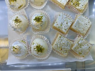 Delicious dessert assortment featuring sweets adorned with silver leaf, displayed in a tray at a local bakery during daylight hours