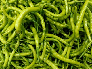 Fresh green chilies piled together in a vibrant market display, showcasing the rich texture and color of these spicy ingredients