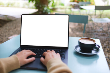 Mockup image of a woman working and typing on laptop computer with blank white desktop screen in...