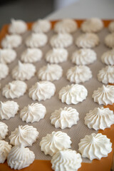 Top view of white meringue cookies on baking tray