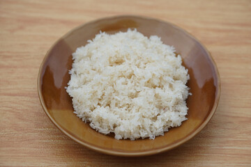 Steamed sticky rice served on a rustic brown ceramic plate. Concept,staple Asian carbohydrate dish that represents energy, nutrition, culture, and culinary heritage. Traditionally cooked by steaming. 