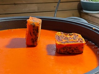Two solid Sichuan hot pot base cubes, embedded with chili peppers, Sichuan peppercorns, and beef...