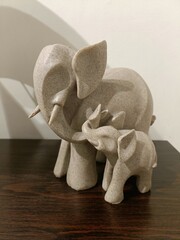 Elephant sculpture representing a mother and her calf made from natural stone displayed on a wooden...