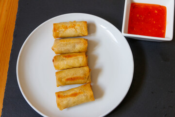Vegetable filled thai spring rolls and sweet chili sauce on a table. Top view