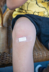 The child has a wound on his knee covered with a bandage