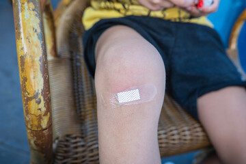 The child has a wound on his knee covered with a bandage