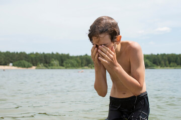 A little boy eats food on the beach after swimming