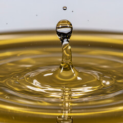 Golden Splash: Macro Shot of Liquor Droplet Creating Waves on Gold Surface.