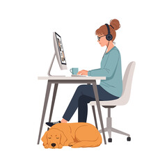A woman with headphones works at a computer while her golden retriever dog sleeps at her feet.