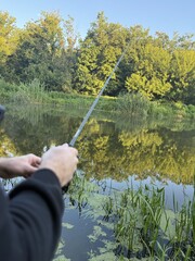 Early summer morning, a guy aged 20-35 catching pike with a spinning rod