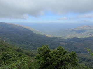 Obraz premium Scenic view of rolling hills and lush valleys under a cloudy sky in the early morning light near the mountains