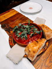 Delicious homemade tomato stew served with fresh bread on a wooden table