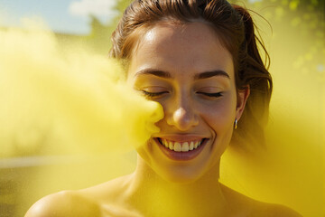 Happy woman with her eyes closed smiling blissfully while enveloped in a cloud of vibrant yellow powder, a moment of pure joy and freedom during a color festival