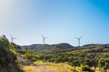 Wind turbines on green hills under a clear blue sky in Turkiye. The landscape features lush...