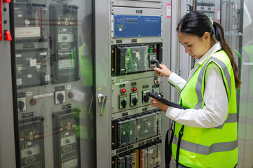 Electrical protection relay power station inspection by technician in safety vest checking control...