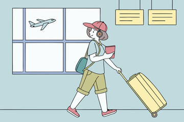 Young tourist pulling vibrant rolling suitcase near flight board in airport, wearing casual vacation clothing