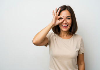 Fototapeta premium smiling woman making ok hand gesture over eye symbolizing vision check. national eye exam month concept. health awareness, healthcare campaign.