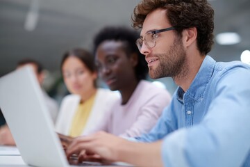 Diverse business team collaborating on digital marketing strategy using laptops and tablets in a bright office