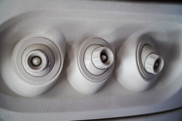 Close-up view of airplane's circular air vents with adjustable knobs set against a textured,...