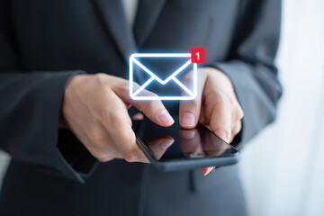 Person in suit holding smartphone with email notification icon hovering above the device screen