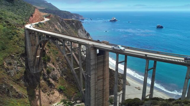 Cars drive across Bixby Bridge, a concrete arch bridge in Big Sur, California, USA. The bridge provides access along the scenic Highway 1 route.