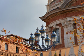 Elegant vintage street lamp with five ornate lanterns framed by autumn leaves and historic red...