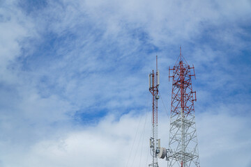 Telecommunication towers rise against a vibrant blue sky dotted with fluffy clouds, symbolizing...