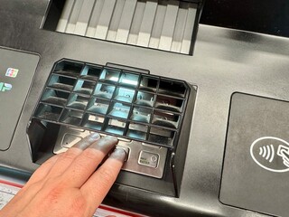 A person dials a PIN code at an ATM. High quality photo