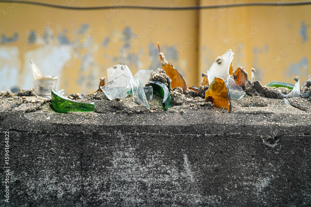 Poster an artistic display featuring shards of broken glass embedded in gritty sand on a weathered concrete